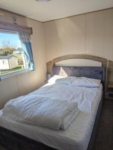 a bedroom with a large bed with a window at Caravan sleeps 8 at Littlesea, Weymouth in Wyke Regis