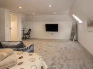 a living room with a couch and a tv on the wall at 85C Bongate in Jedburgh