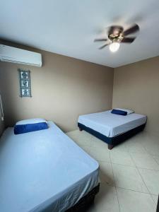 two beds in a room with a ceiling fan at Casa con piscina súper bonita ! in Salinas