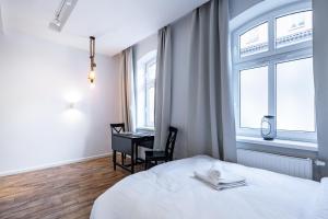 a bedroom with a bed and a desk and windows at Janasa Comfort Studio in Katowice