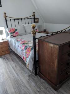 a bedroom with a bed with a wooden dresser at Craigmile Cottage in Fraserburgh