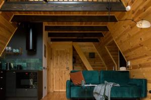 a living room with a green couch and wooden ceilings at Samosiejka - Lewy Brzeg Narwi in Burlaki