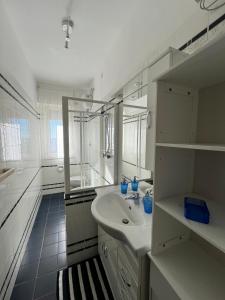 uma casa de banho branca com um lavatório e um espelho em Finestra sul mare em Monfalcone