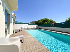 a swimming pool with white chairs next to a house at Villa Primavera in Lagos