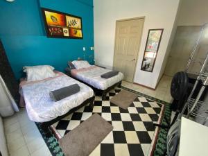 two beds in a room with a checkered floor at Habitación doble Hotel Chapultepec-Americana in Guadalajara