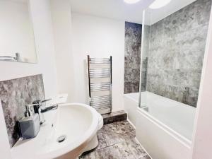 een witte badkamer met een wastafel en een bad bij Stylish Cambridge Apartment with Garden in Cambridge