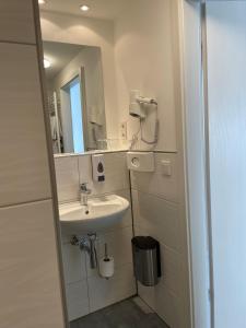 a white bathroom with a sink and a mirror at Hotel Frankenhöhe in Aurach
