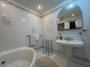 a bathroom with a tub and a sink and a mirror at Seaview Serenity 3-Bedroom Apt view over Valletta Harbour in Sliema