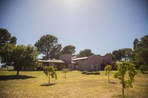 a house with trees in front of a yard at La Posta Hotel de Campo in Tres Lomas