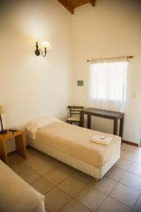 a bedroom with two beds and a table and a window at La Posta Hotel de Campo in Tres Lomas