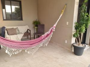 a hammock in a living room with a couch and a chair at Quarto em casa com lazer completo in Indaiatuba