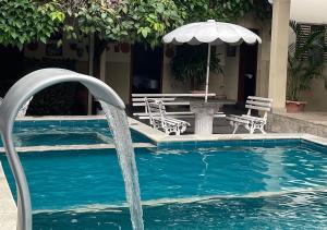 een zwembad met een parasol en een tafel bij Pousada Tropical in Barra do Garças