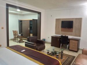 Immaculate Diamond Hotel & Apartments في أبوجا: غرفة نوم بسرير ومكتب وكراسي