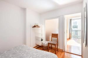 um quarto branco com uma cama e uma cadeira em Apartamento em Alfama - Centro Histórico em Lisboa