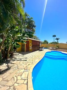 a swimming pool in front of a house with palm trees at Pousada Bosque dos Papagaios in Búzios