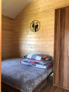 łóżko w drewnianym domku z zegarem na ścianie w obiekcie Mazurski domek w mieście Mrągowo