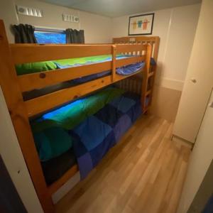 a bedroom with a bunk bed with green and blue sheets at Het Bruggetje Leekstermeer in Matsloot