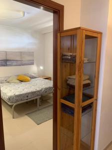 1 dormitorio con cama y estantería de madera en Los Cristianos Apartamento en residencial Los Seres, en Los Cristianos