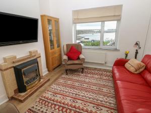 sala de estar con sofá rojo y chimenea en Cooper Cottage en Neyland