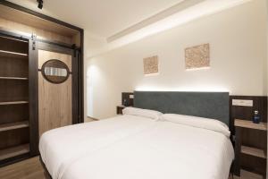 a bedroom with a large white bed and a mirror at Hotel A Mares in Celorio