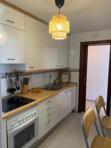 een keuken met witte kasten, een wastafel en een kroonluchter bij Los Cristianos Apartamento en residencial Los Seres in Los Cristianos