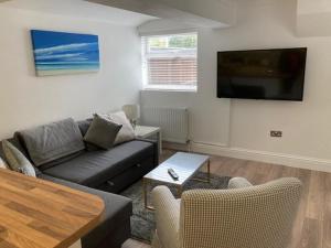 ein Wohnzimmer mit einem Sofa und einem Flachbild-TV in der Unterkunft Highcliffe Apartment with Parking in Christchurch