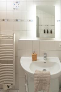 ein weißes Badezimmer mit einem Waschbecken und einem Spiegel in der Unterkunft Ferienwohnung Neuhaus in Wolfsburg