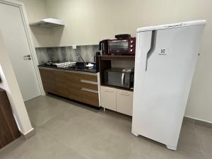 a kitchen with a refrigerator and a microwave at Condomínio Kaimã in Matinhos