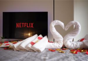 dois cisnes brancos sentados numa cama em frente a uma televisão em Veterani Holidays Cefalù em Cefalù