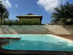 a swimming pool with a house in the background at Chambre Selva in Cayenne