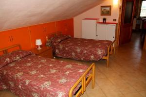 a hotel room with two beds and orange walls at Appartamenti Pian d'Alma in Punta Ala