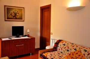 a living room with a couch and a television at Appartamenti Pian d'Alma in Punta Ala