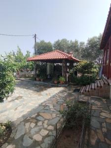 a gazebo with a stone walkway and benches at Stella's Apartment in Áyios Pávlos