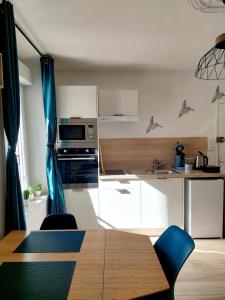 una cocina con mesa de madera con sillas y una cocina con armarios blancos. en ESCALE À ÉPERNAY BORDS DE MARNE APPT 2/4 PERS en Épernay