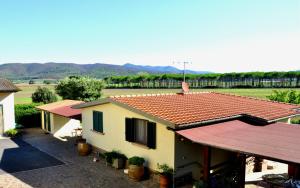 a house with a red roof with a field in the background at Appartamenti Pian d'Alma in Punta Ala