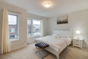 a white bedroom with a bed and two windows at Brand new townhouse, 30 minutes to Downtown in Toronto