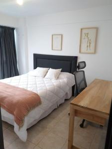 1 dormitorio con cama blanca y mesa de madera en Avenida Premium: Confort y Vistas Excepcionales en San Salvador de Jujuy