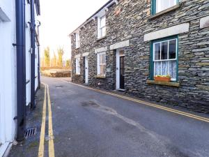 an empty street next to a stone building with a window at Partridge Holme in Bowness-on-Windermere