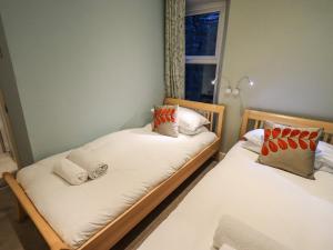 two twin beds in a room with a window at Partridge Holme in Bowness-on-Windermere