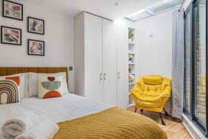 a bedroom with a bed and a yellow chair at 2 bed arty flat at Trafalgar Square in London