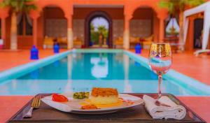 einen Teller mit Essen und ein Glas Wein neben einem Pool in der Unterkunft Dar De Santis in Azemmour