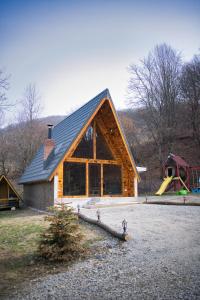 ein Blockhaus mit einem Spielplatz und einer Rutsche in der Unterkunft Cabana A frame Olanesti in Băile Olăneşti