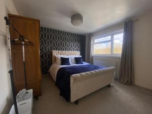 1 dormitorio con 1 cama con manta azul y ventana en 3 Bedroom House en Northampton