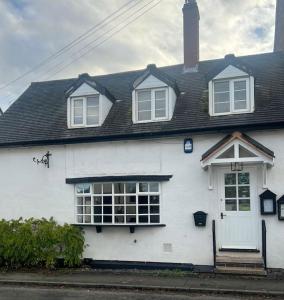 a white house with a black roof at The Cottage, with Superking bed & private patio in Chaddesley Corbett