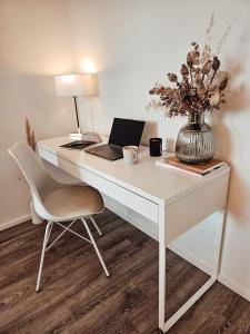 a white desk with a laptop and a chair at Modernes Appartment im Grünen in Witten