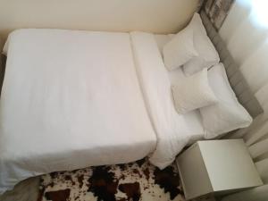 białe łóżko z 2 poduszkami i lampą w obiekcie The Pearl Cage Gigiri-Near US Embassy w mieście Nairobi