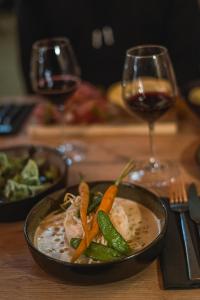 a bowl of soup with vegetables and a glass of wine at Hotel Le Beau Site in Auris