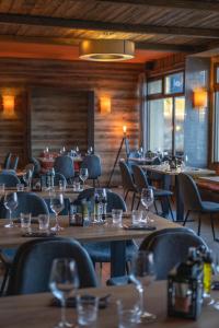 a restaurant with wooden tables and chairs with wine glasses at Hotel Le Beau Site in Auris