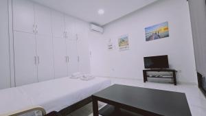 een witte kamer met 2 bedden en een televisie bij STAY Cypress Studio in Limassol