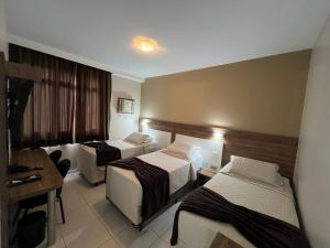 a hotel room with two beds and a desk at Brisamar Suite Hotel in Florianópolis +42 photos